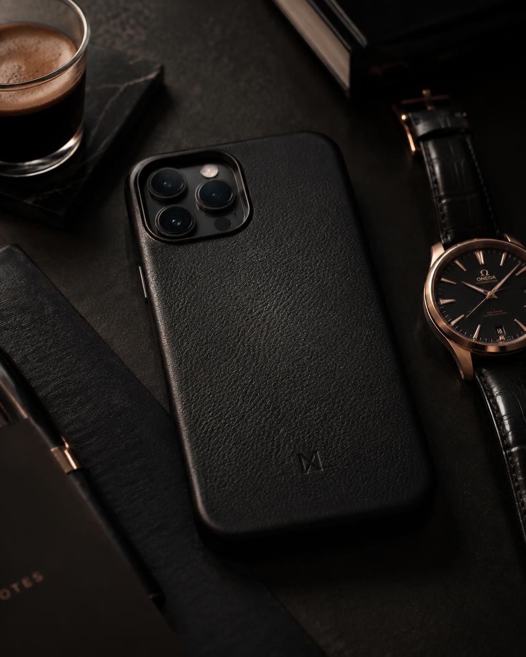 Black leather case beside a watch on a dark desk